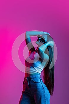 Young beautiful girl in motion  on pink purple background