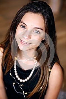 Young beautiful girl near a New Year tree smiles joyfully. Close-up portrait. Merry Christmas and holidays.