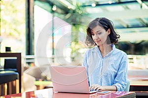 Young and beautiful girl with notebook and laptop sitting in a cafe