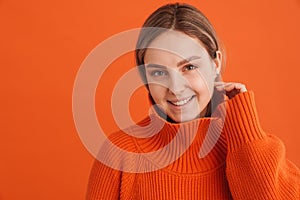 Young beautiful girl in orange sweater touching her cheek