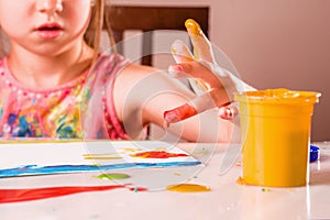 Young beautiful girl painting image with colorful hands and finger. Happy childhood, art, drawing concept. Selective focus on