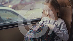 Young, beautiful girl passenger with school bag in the moving school bus using social network on her smartphone and