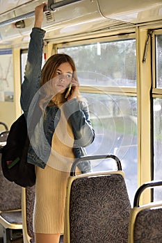 Young beautiful girl passenger using mobile phone in modern tram