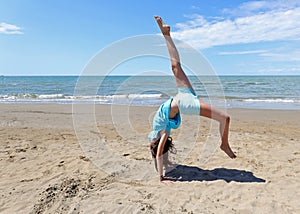 Young beautiful girl performs a wheel with her legs in the air b photo