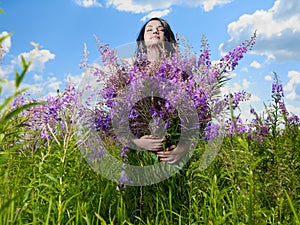 Young beautiful girl picks flowers in the field