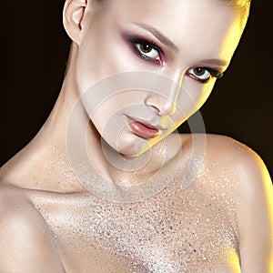 Young beautiful girl with pink make-up and glitter in decolletage zone