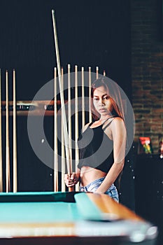 Young beautiful girl playing billiard in a club