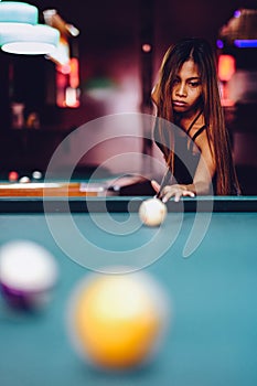 Young beautiful girl playing billiard in a club