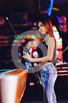 Young beautiful girl playing billiard in a club