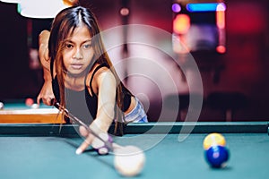 Young beautiful girl playing billiard in a club