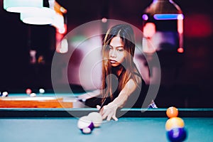 Young beautiful girl playing billiard in a club