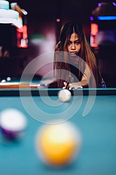 Young beautiful girl playing billiard in a club