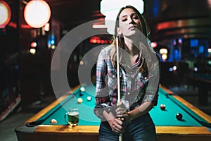 Young beautiful girl is playing billiards. Pleasant pastime, rest, entertainment.