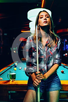 Young beautiful girl is playing billiards. Pleasant pastime, rest, entertainment.