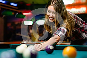 Young beautiful girl is playing billiards. Pleasant pastime, rest, entertainment.