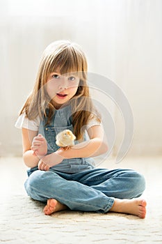 Young beautiful girl, playing with little newborn chick at home