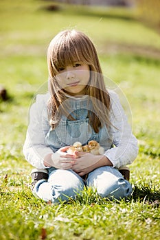 Young beautiful girl, playing with little newborn chick in the p