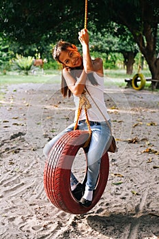 Young beautiful Girl Playing On Tire Swing In the farm