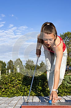 Young beautiful girl plays golf on a sunny day