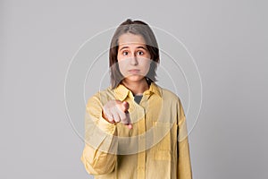 Young beautiful girl pointing with finger to the camera and to you, confident gesture looking serious