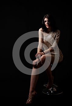 Young beautiful girl posing sitting on chair in the studio
