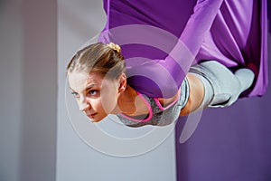 Young beautiful girl practicing aerial yoga in gym