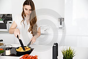 Young, Beautiful Girl is Preparing Breakfast in a Modern, White Kitchen. Omelet and Seasoned Vegetables on Countertop