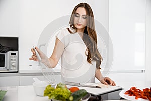 Young, Beautiful Girl is Preparing Breakfast in a Modern, White Kitchen. Omelet and Seasoned Vegetables on Countertop.