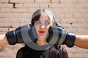 Young and beautiful girl with a punky tendency. She is being hit on each side of her face with boxing gloves. The girl is doing