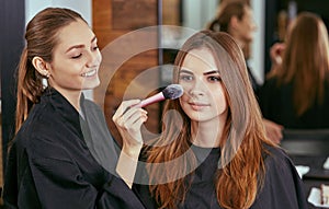 Young, beautiful girl put on make-up in a beauty salon