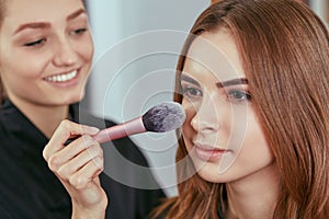 Young, beautiful girl put on make-up in a beauty salon