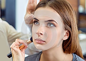 Young, beautiful girl put on make-up in a beauty salon