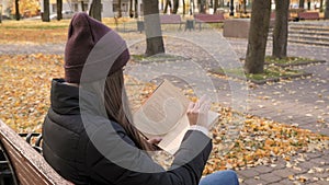 Young beautiful girl reading book in autumn park