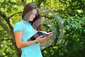 Young beautiful girl reading book in a park