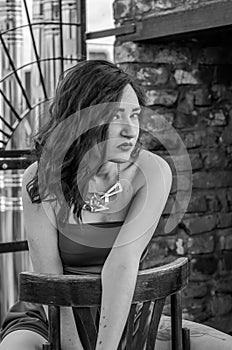 Young beautiful girl in a red dress is sitting on a wooden chair in a cafe on a street in the city of Lviv