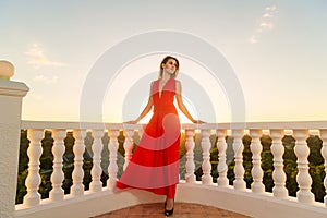 Young beautiful girl in a red dress standing next to the stone g