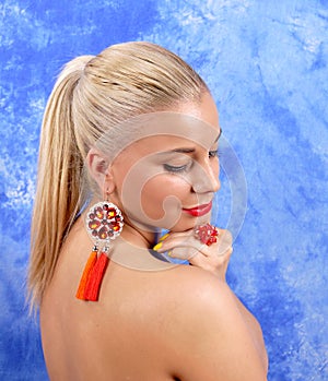 Young beautiful girl in red earrings on an abstract background