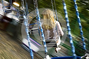 Young beautiful girl rides on a swing suspended on chains.