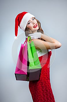 Young beautiful girl in santa hat with shopping bags