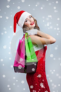 Young beautiful girl in santa hat with shopping bags