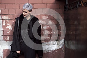 Young beautiful fashion girl shooting outdoors near brick wall at home