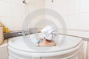 Young beautiful girl showering in bathtub.