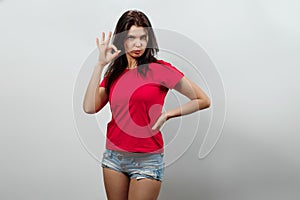 Young, beautiful girl showing hands gesture ok. Isolated on a light background. Different human emotions, feelings of facial