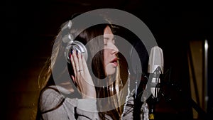 Young beautiful girl sings.Young singer singing into a microphone.Portrait close up of the singer.Recording studio