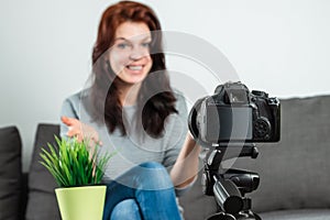 A young beautiful girl is sitting in front of a DSLR and recording a Vlog, close-up. Blogger, blogging, technology, online money,