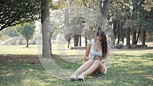 Young Beautiful Girl Sitting On Lawn In Park Using Tablet PC, On-line Shopping Concept