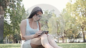 Young Beautiful Girl Sitting On Lawn In Park Using Tablet PC, On-line Shopping Concept