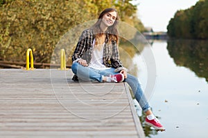 Young beautiful girl sitting on a pier