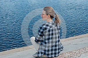 Young beautiful girl sitting on a pier, secluded relaxation concept