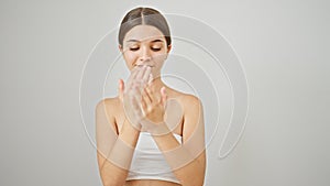 Young beautiful girl smiling confident applying skin lotion on hands over isolated white background